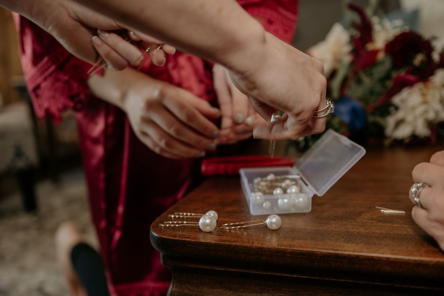 Hands holding playing cards around a wooden table during a game.
