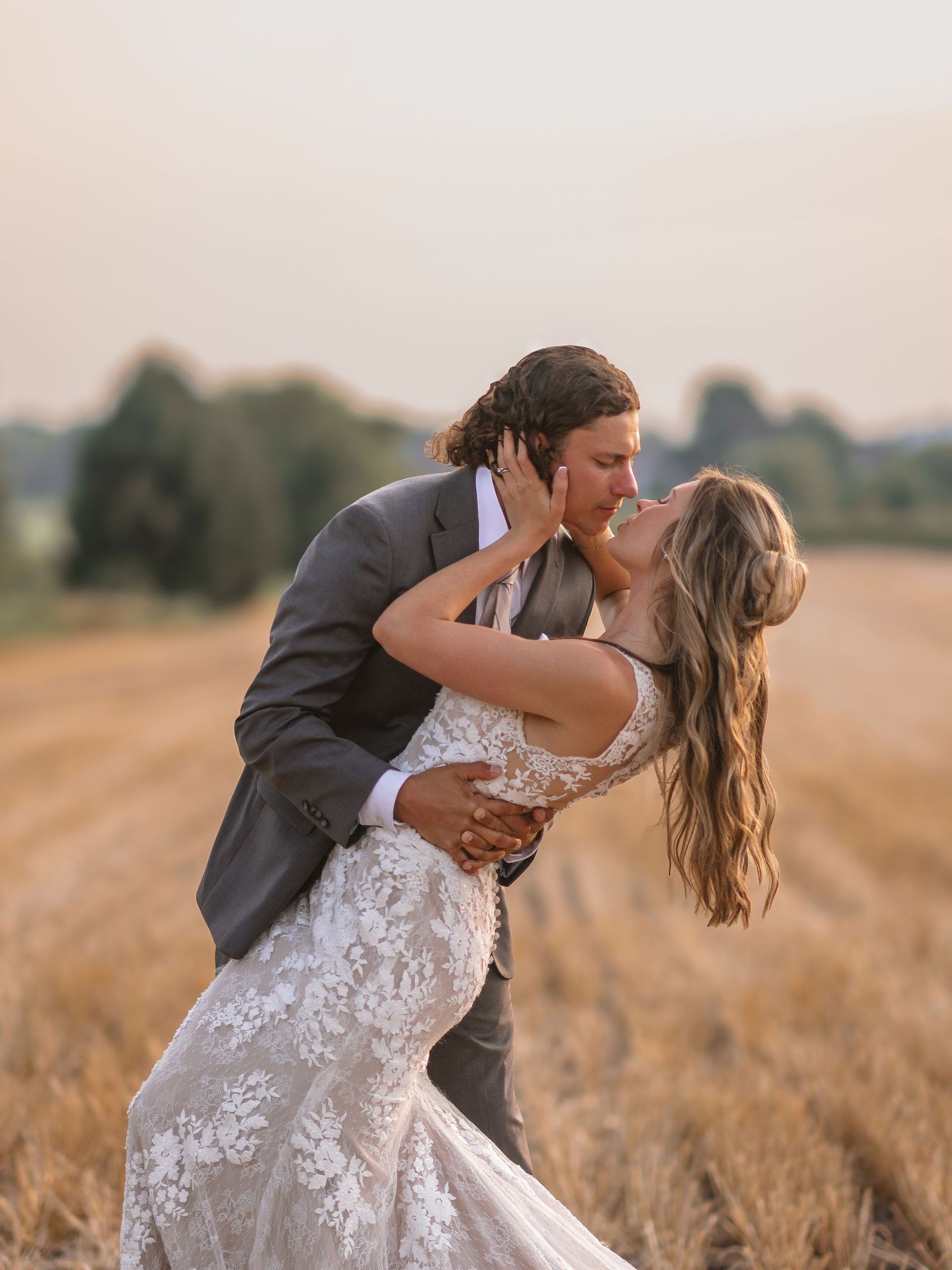 Romantic sunset photos of newlyweds dancing in a golden wheat field.
