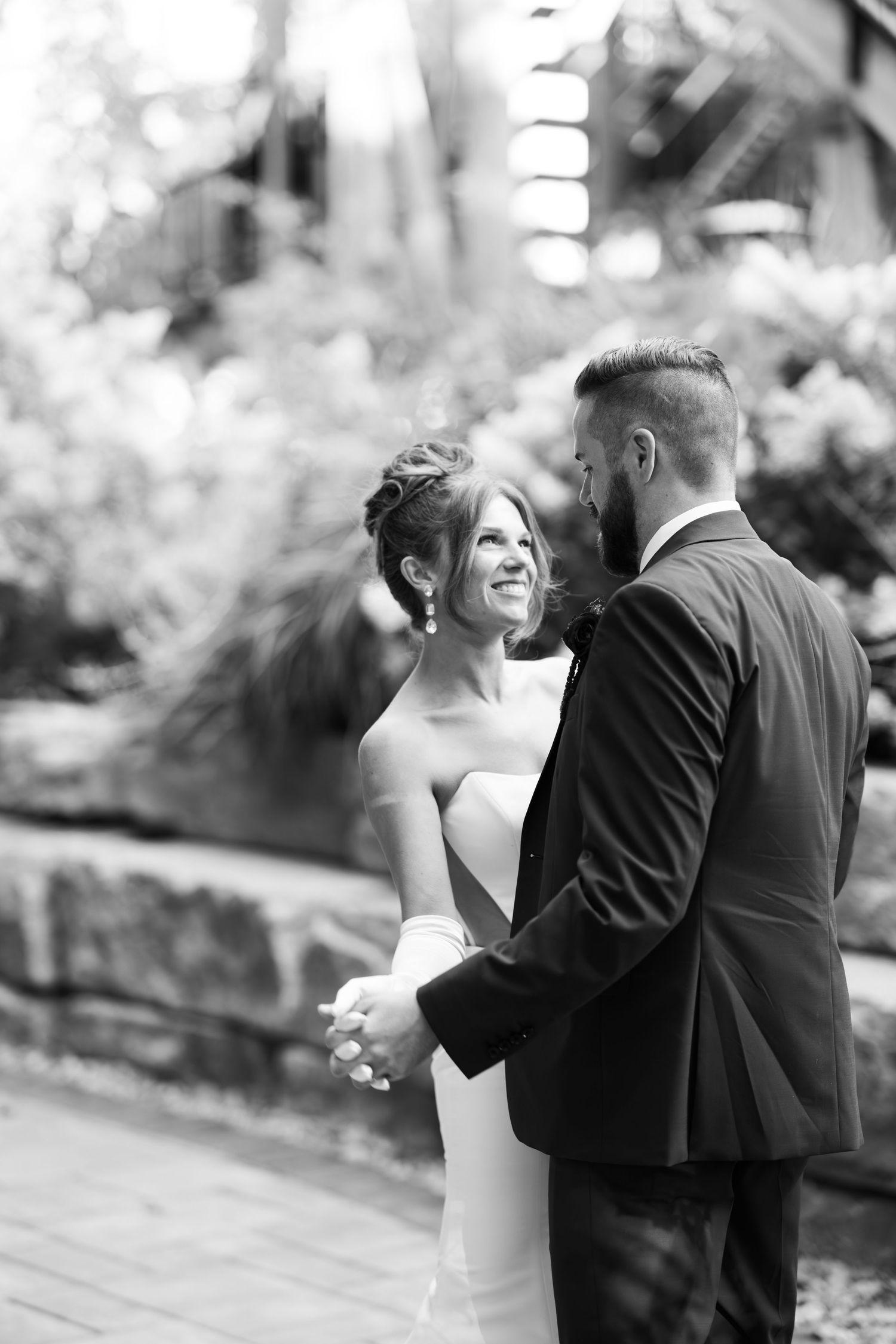 A tender black and white moment between newlyweds sharing joyful laughter during their outdoor wedding ceremony.