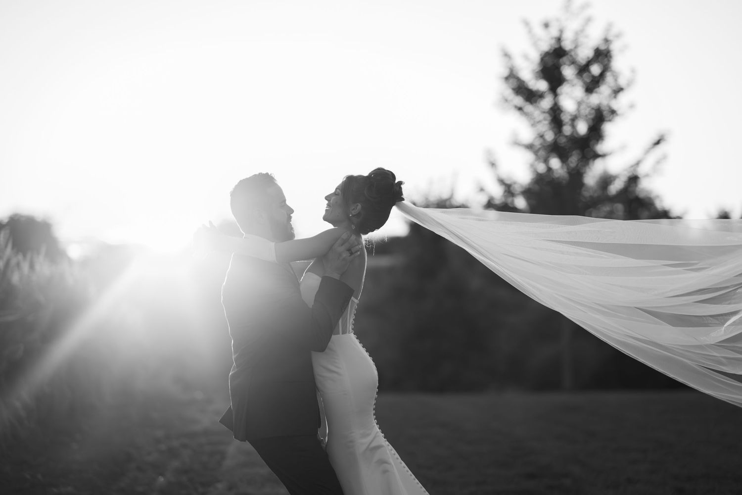 Silhouettes holding flowing fabric against bright sunlight in an artistic outdoor shot.