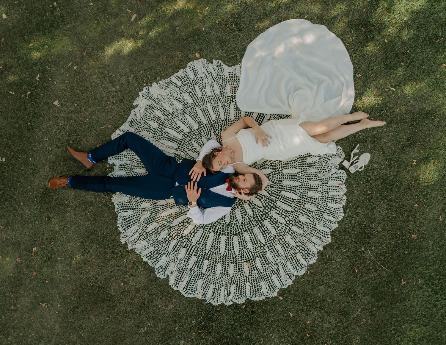 Overhead drone shots showing white wedding dress creating circular patterns on green grass.