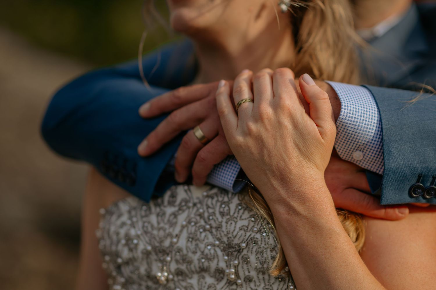 Close-up of hands holding a gray knit blanket while sitting on a couch.