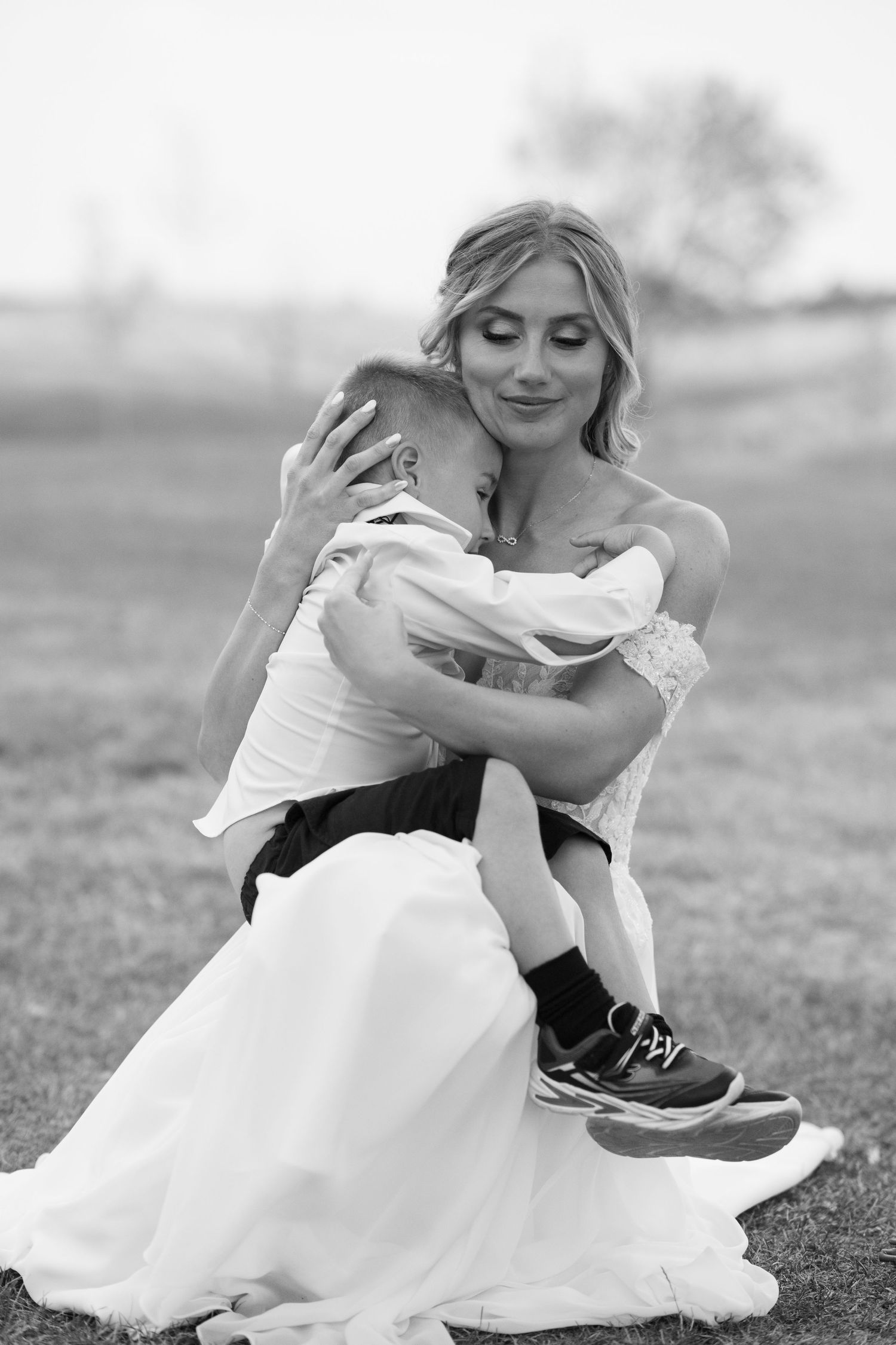 Black and white portraits of playful wedding moments on grassy field.