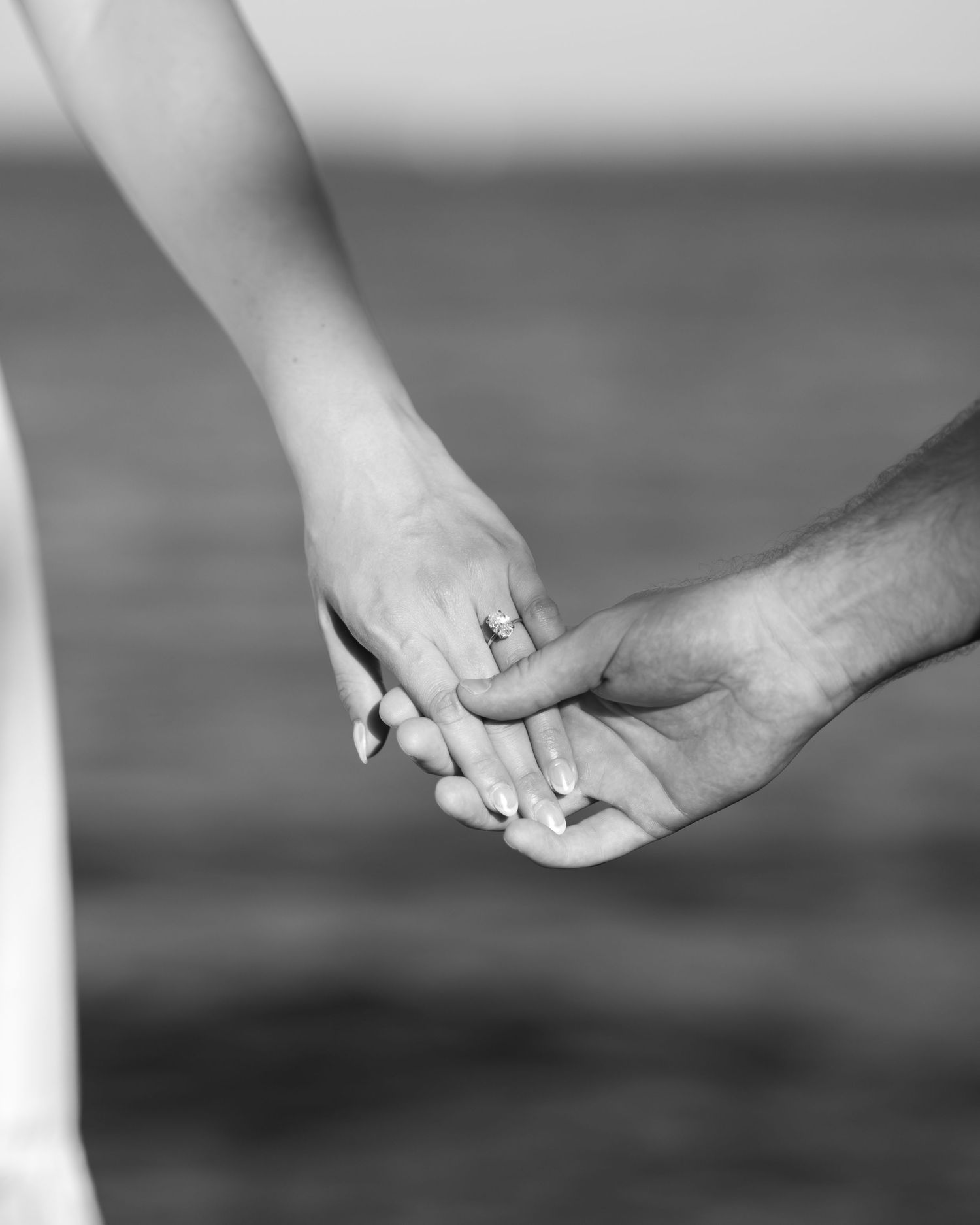 Black and white close-up of hands reaching toward each other over water.