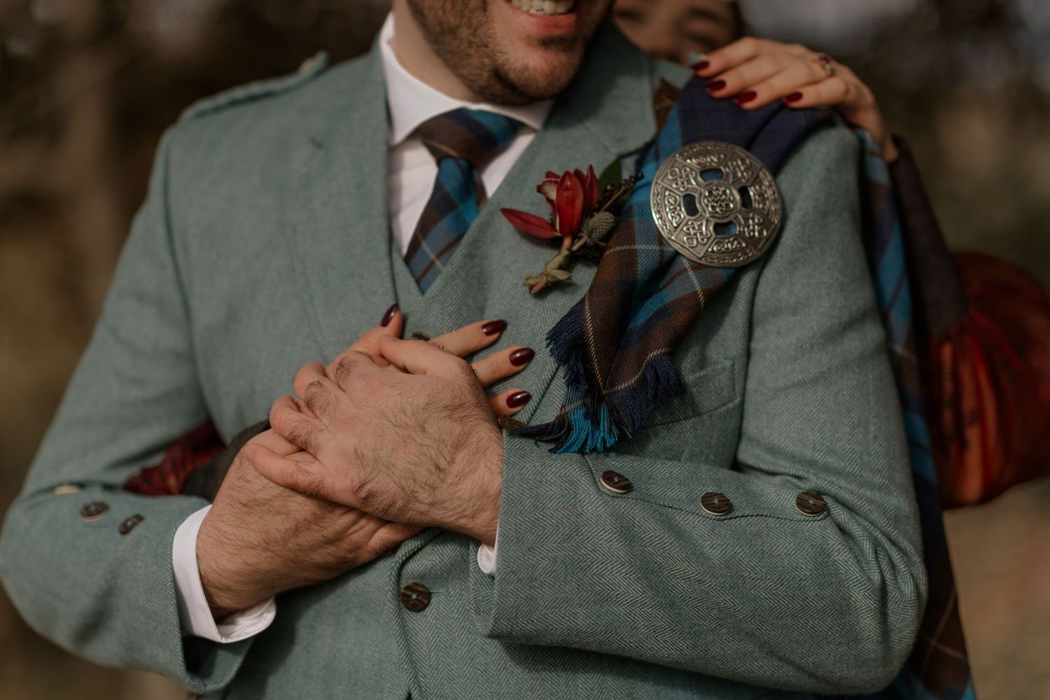 A person wearing a gray suit jacket holds a small butterfly in their hands against a dark background.