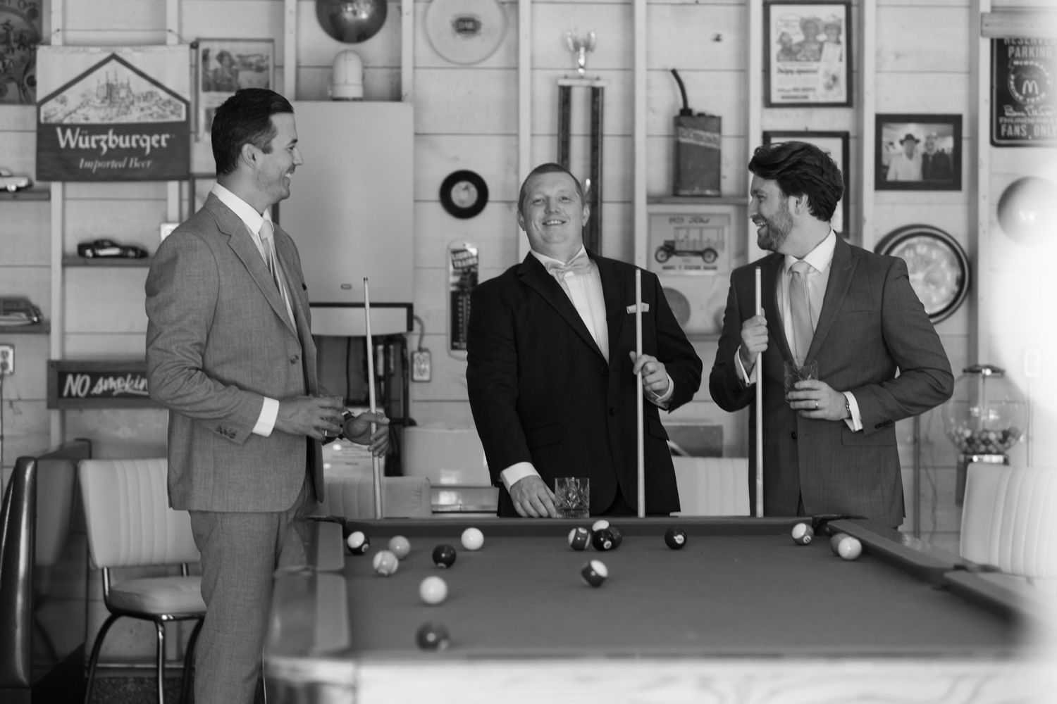 A vintage black and white photograph showing people gathered in a room with clocks and framed items on the walls.