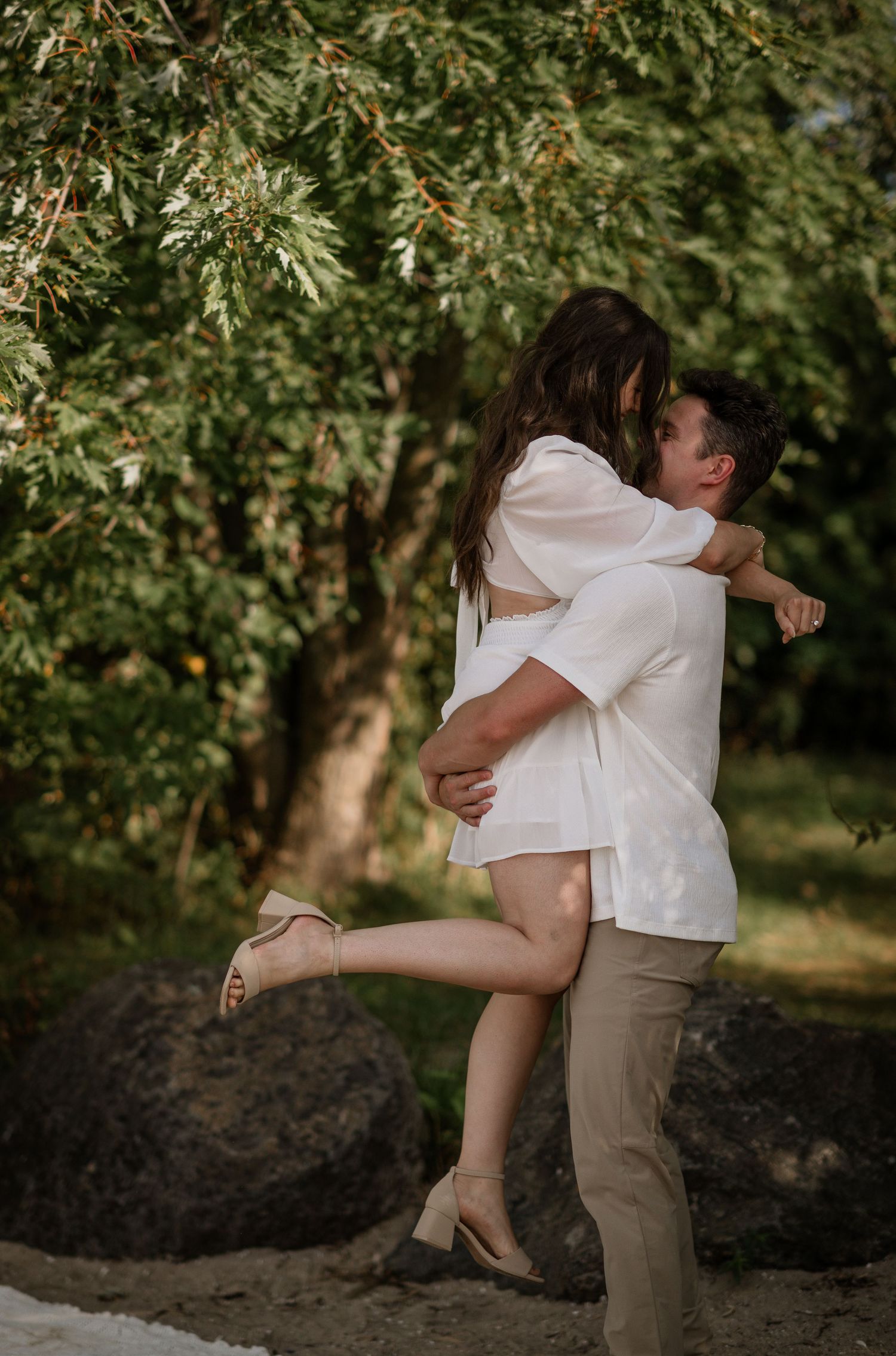 Couple sharing a passionate moment in a lush green garden setting.
