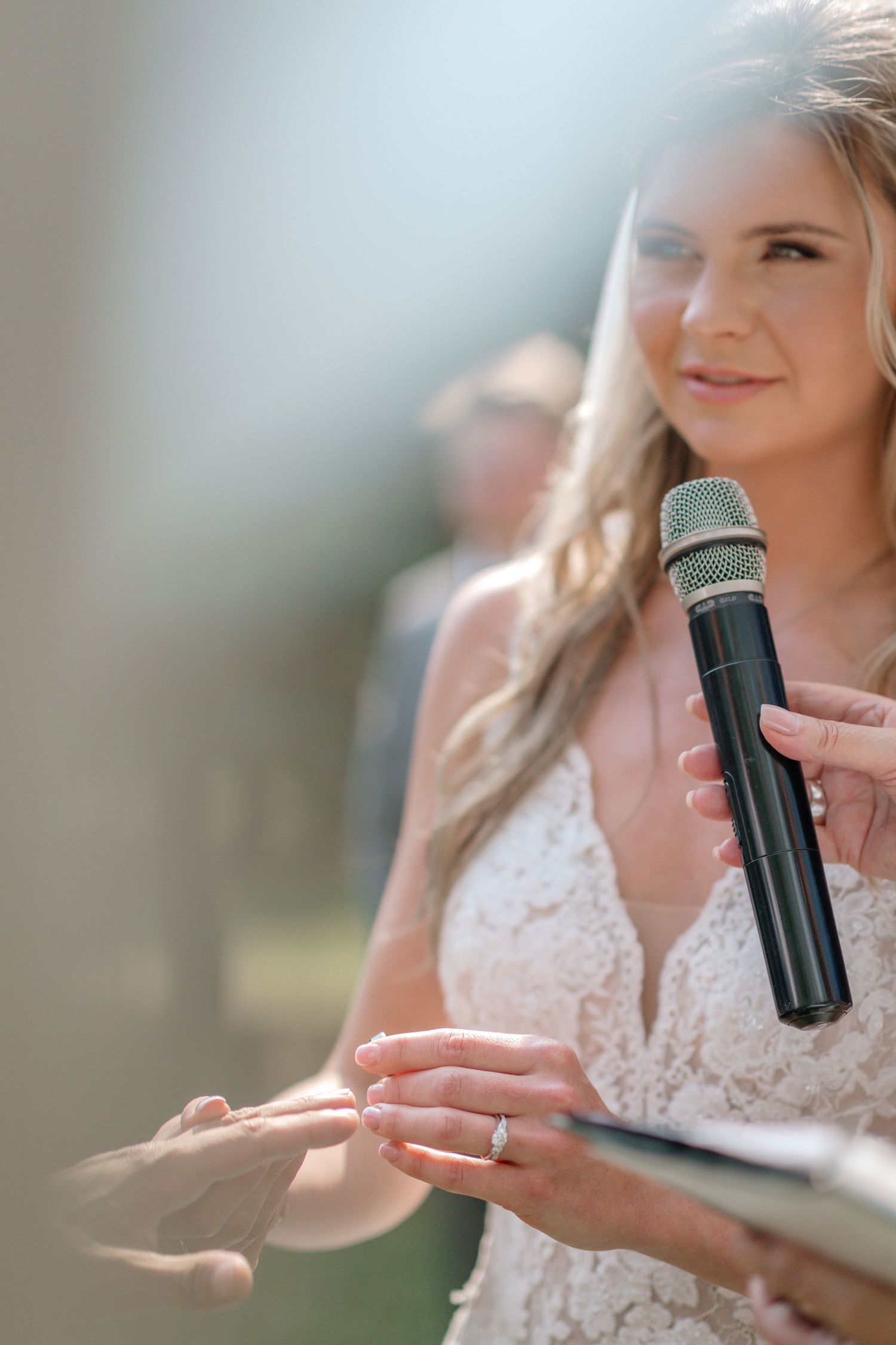 Bride in lace dress holding a small black object during wedding preparations.