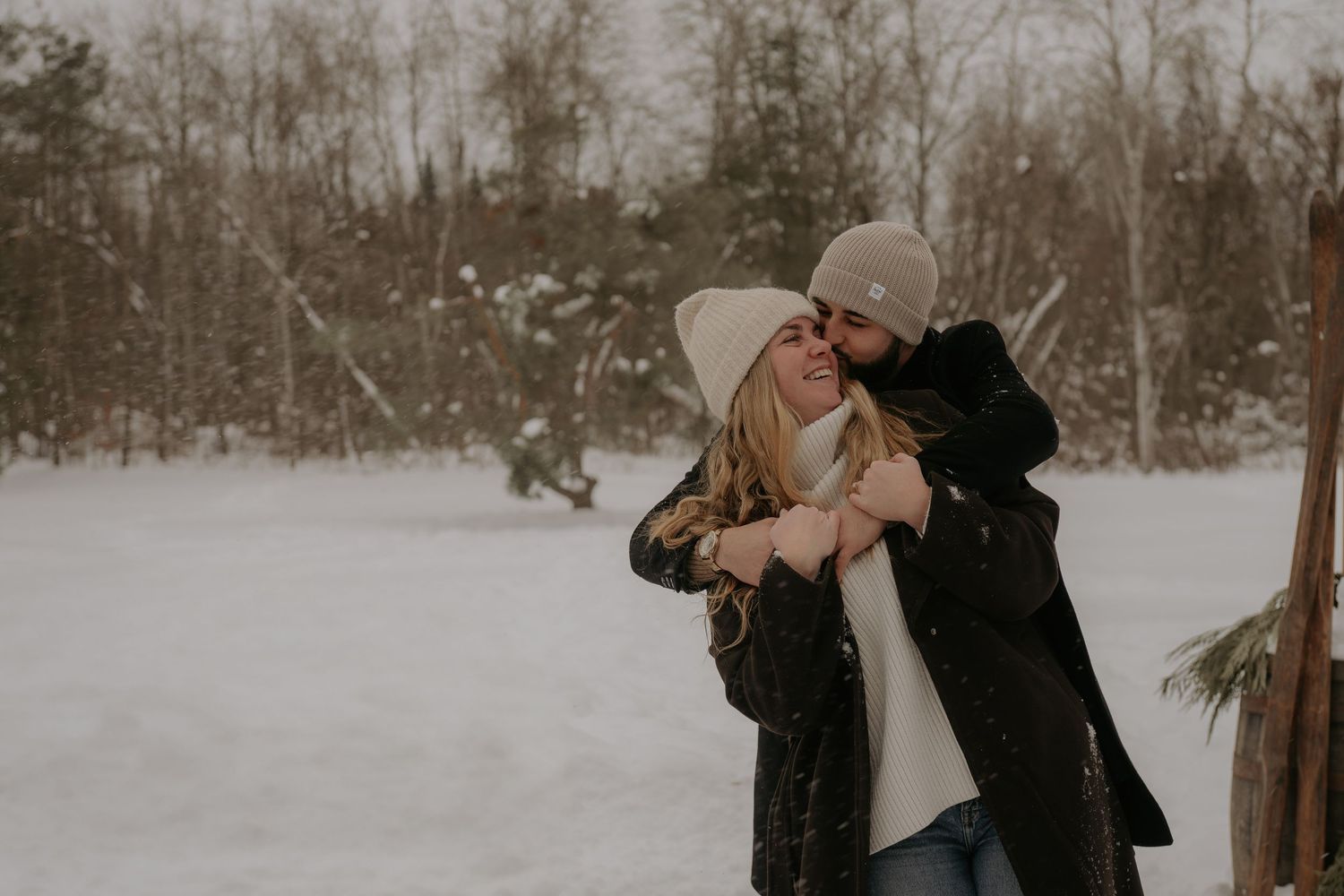 Couple embracing in a snow-covered forest during winter.