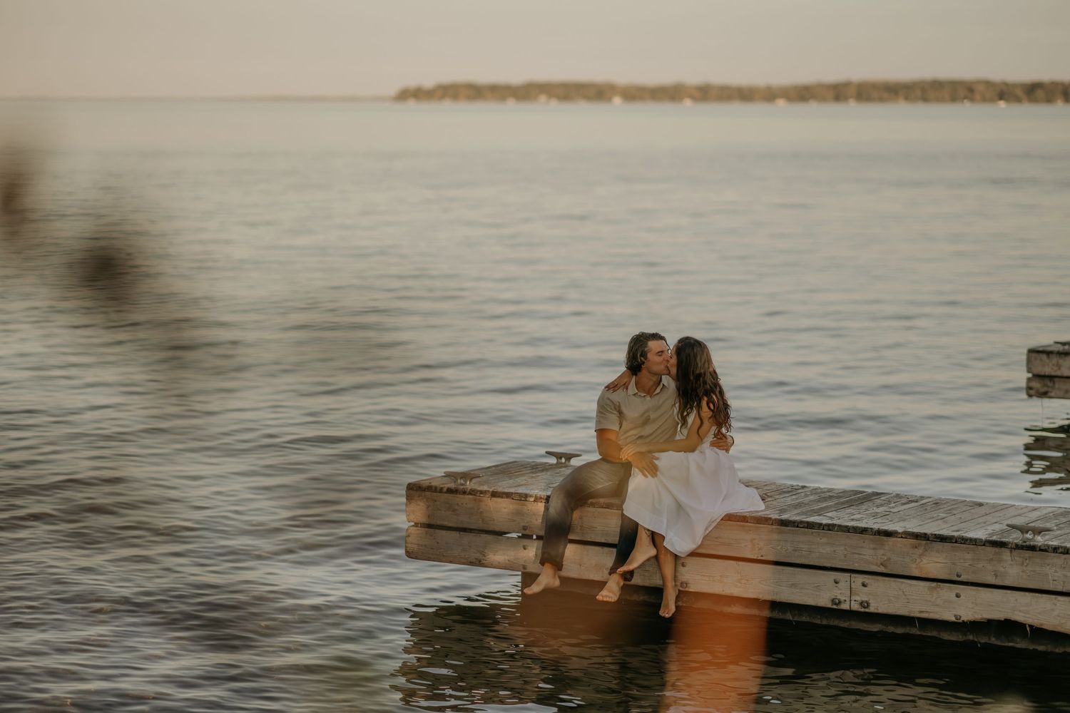 Couple enjoying a romantic sunset swim in calm waters with a warm golden glow.