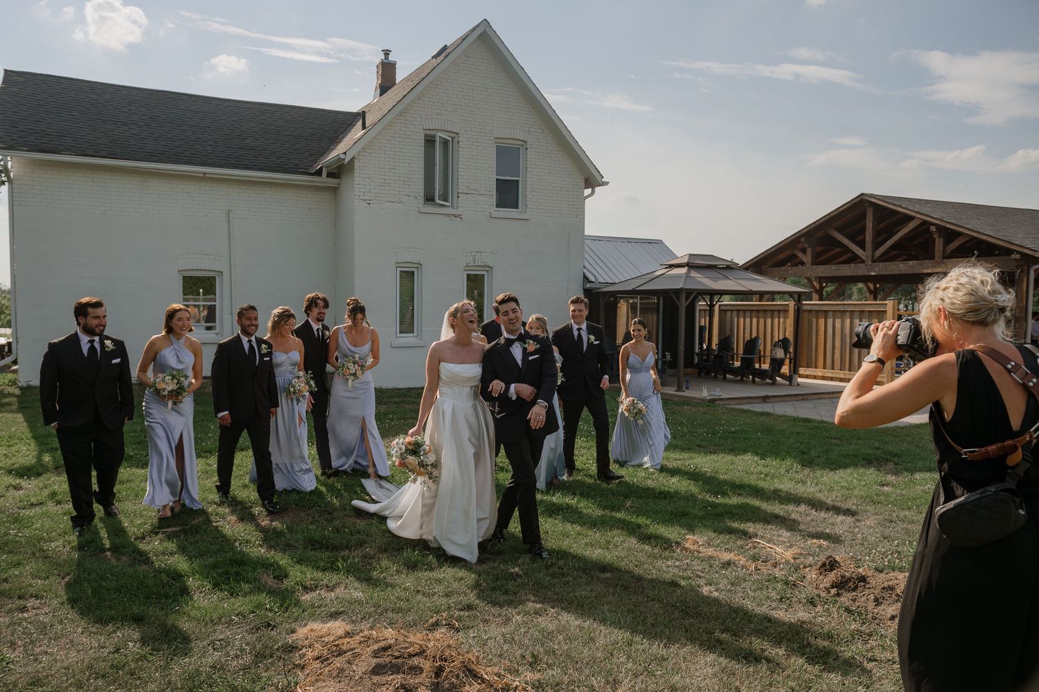 Wedding guests gather outside a white church building on a sunny day for an outdoor celebration.