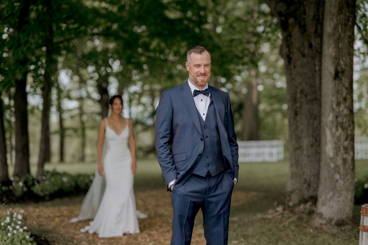 Wedding couple shares an intimate first look moment in a wooded outdoor setting.