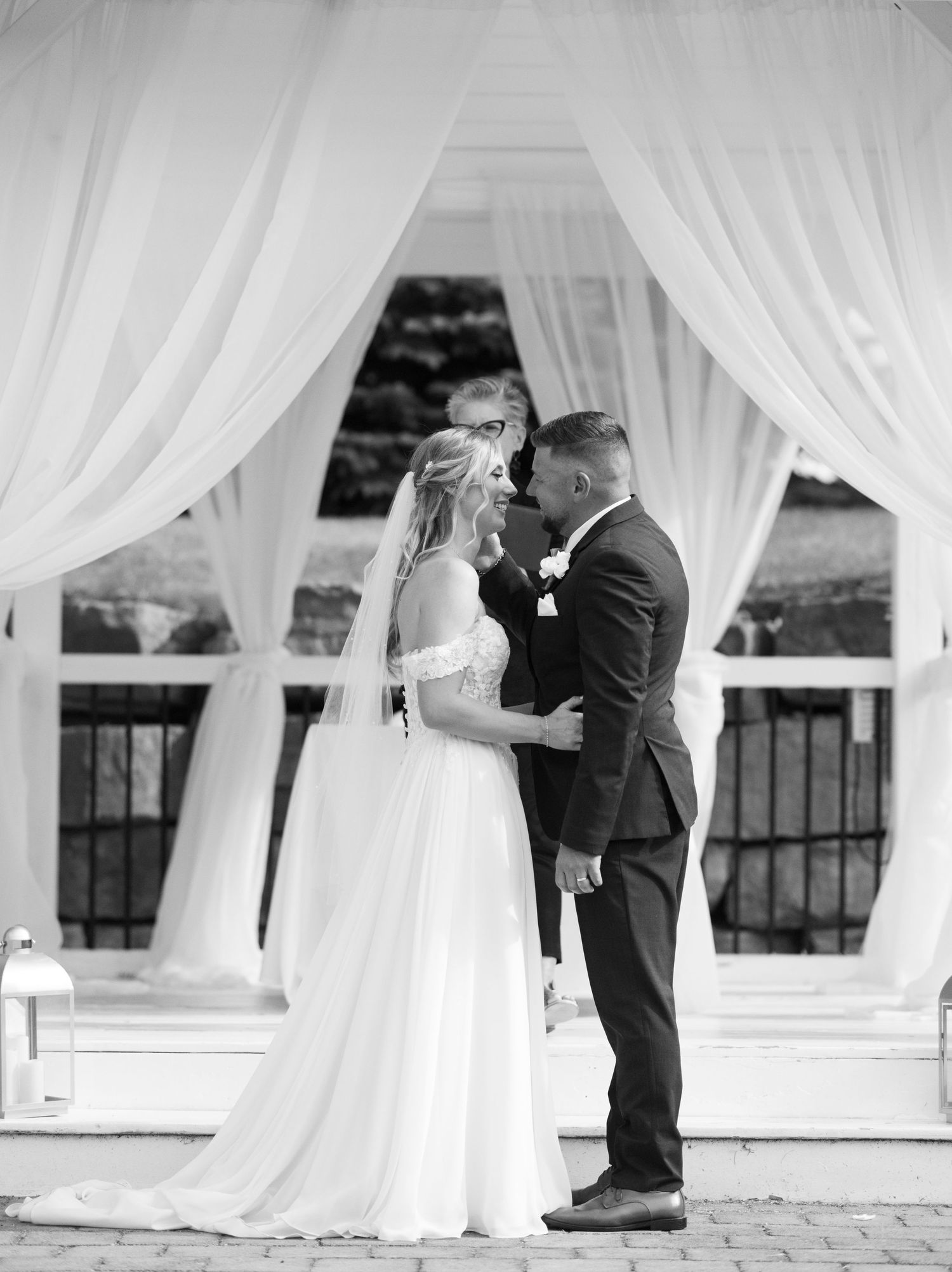 Romantic moment under white draped wedding ceremony backdrop.