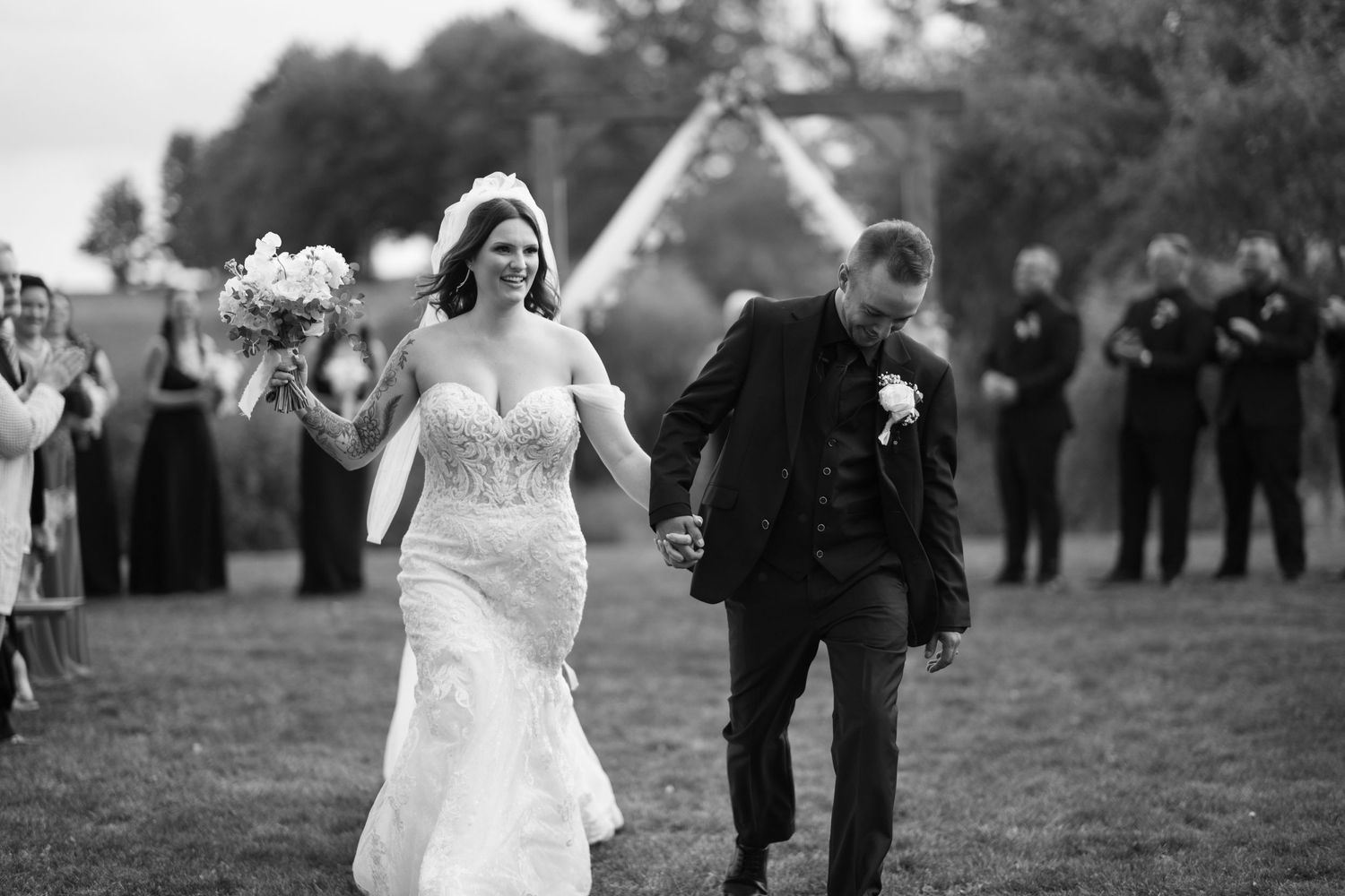 Wedding celebration captured in black and white on a grassy field.
