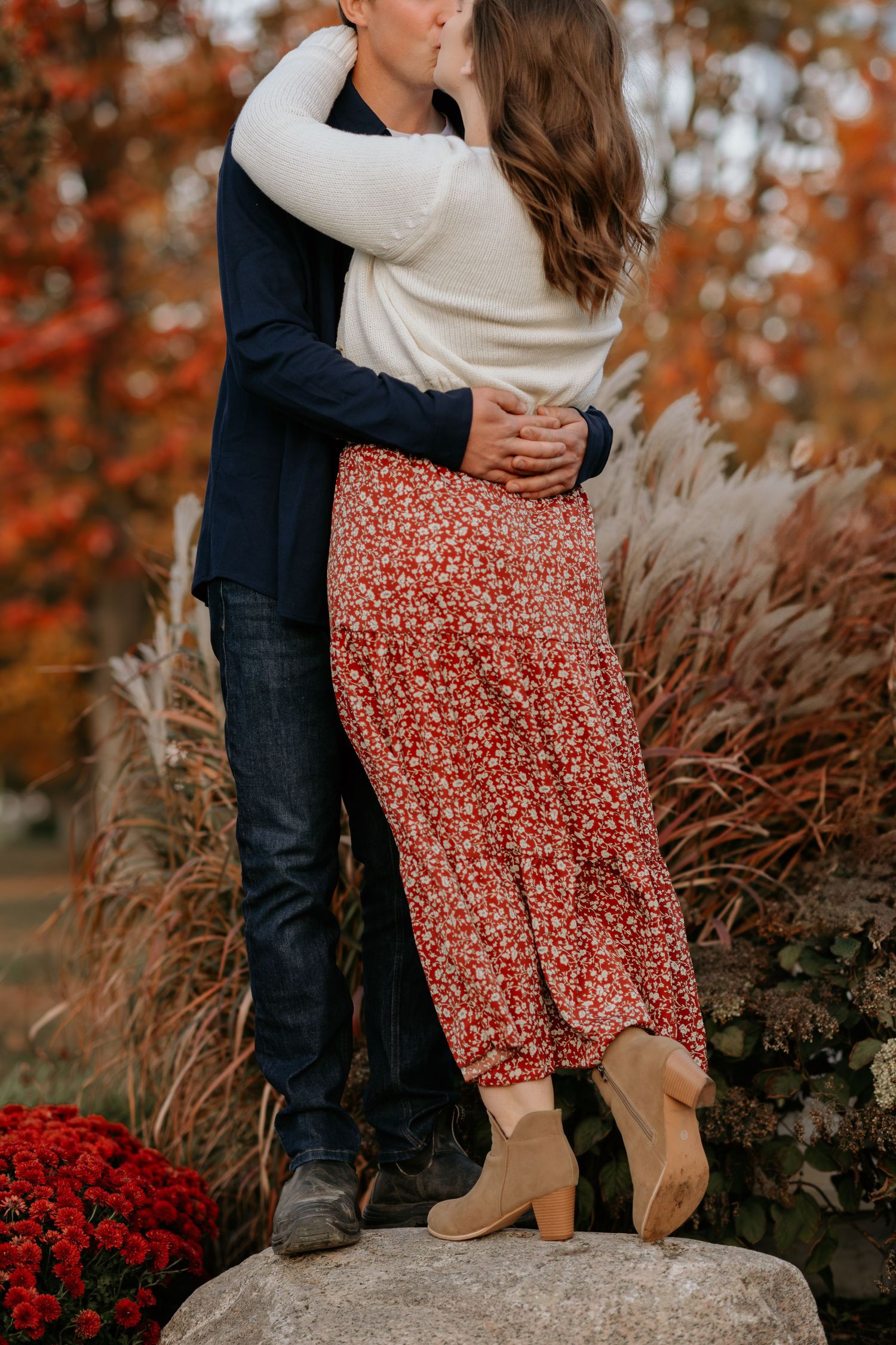 Couple standing close together near decorative grasses during autumn season.