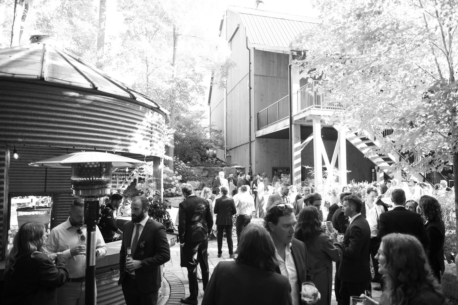Outdoor wedding venue with guests mingling under covered walkways.