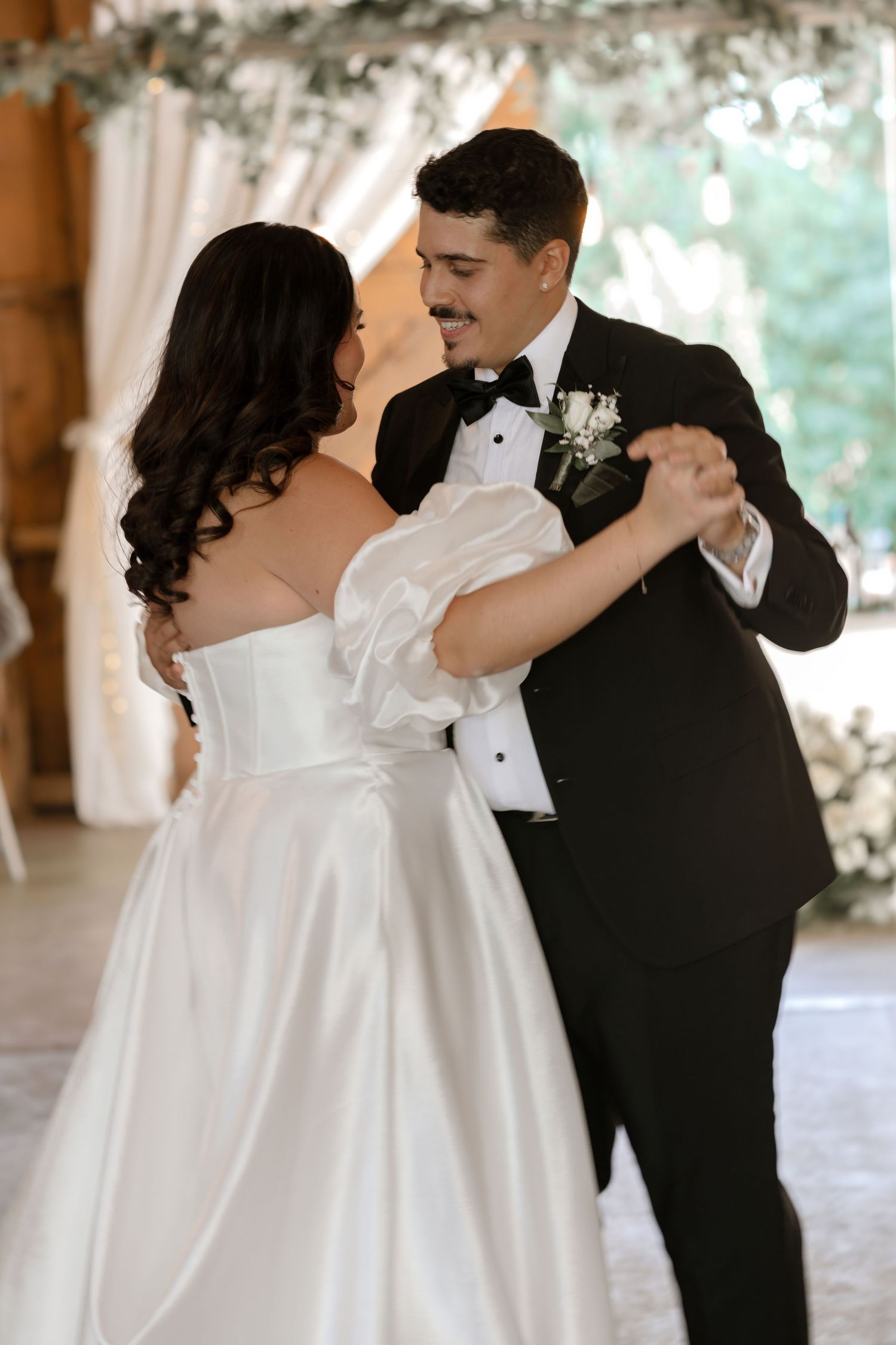 A romantic first dance moment between newlyweds in classic white gown and black tuxedo.