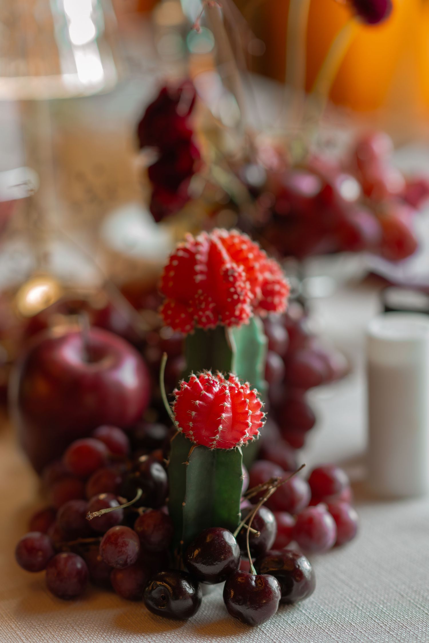 Close-up of red flowers and fresh fruit table decor with grapes, cherries and apples.