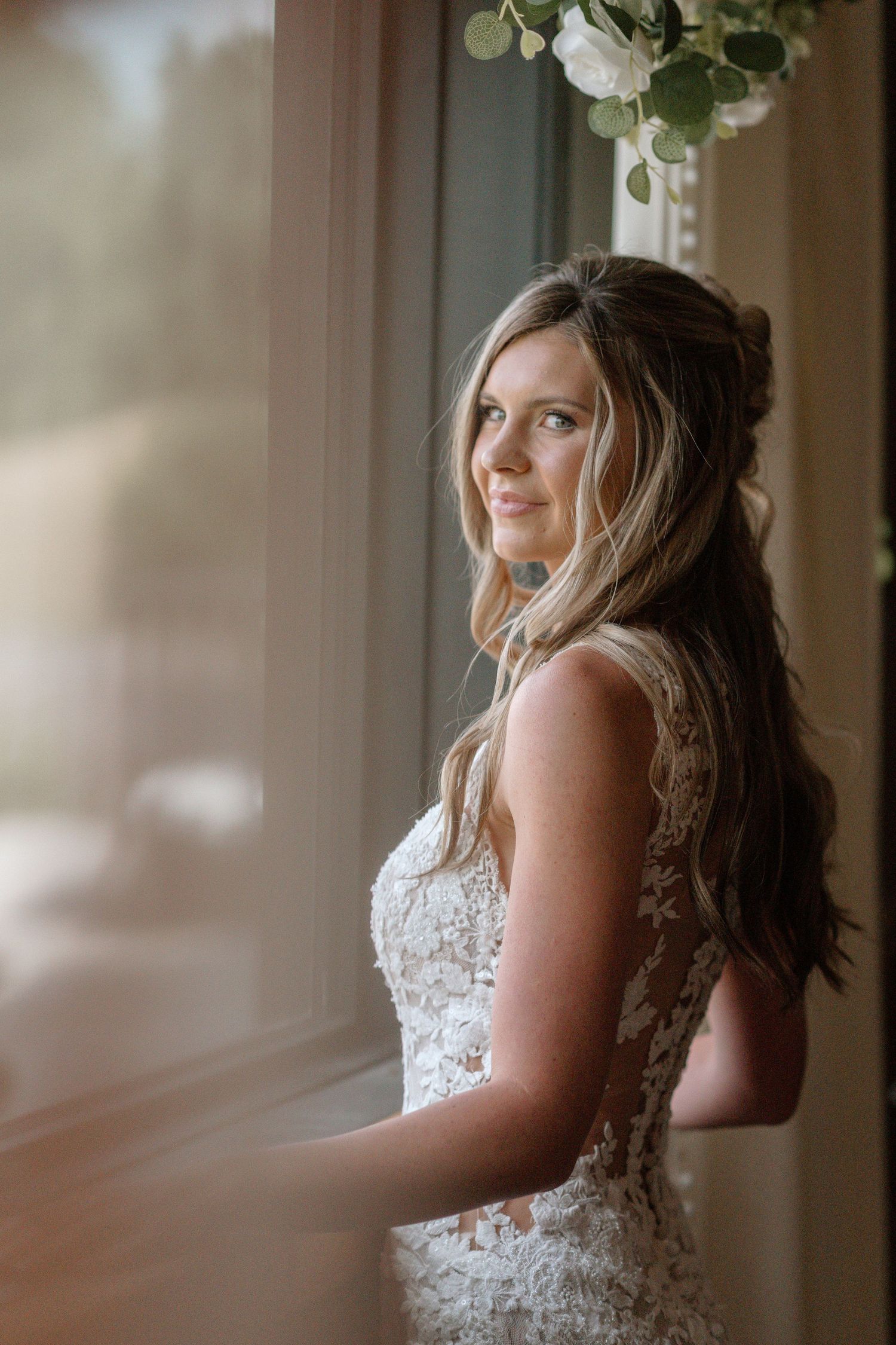 A lace wedding dress detail shot by a window in soft natural light.