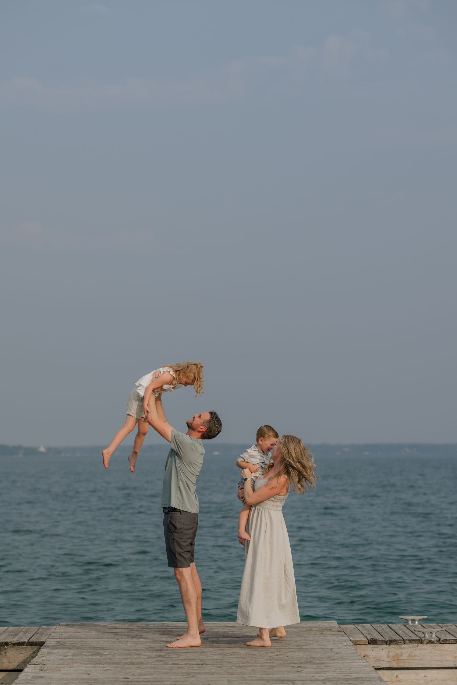 Couple dancing and playing together on a wooden pier by the ocean.