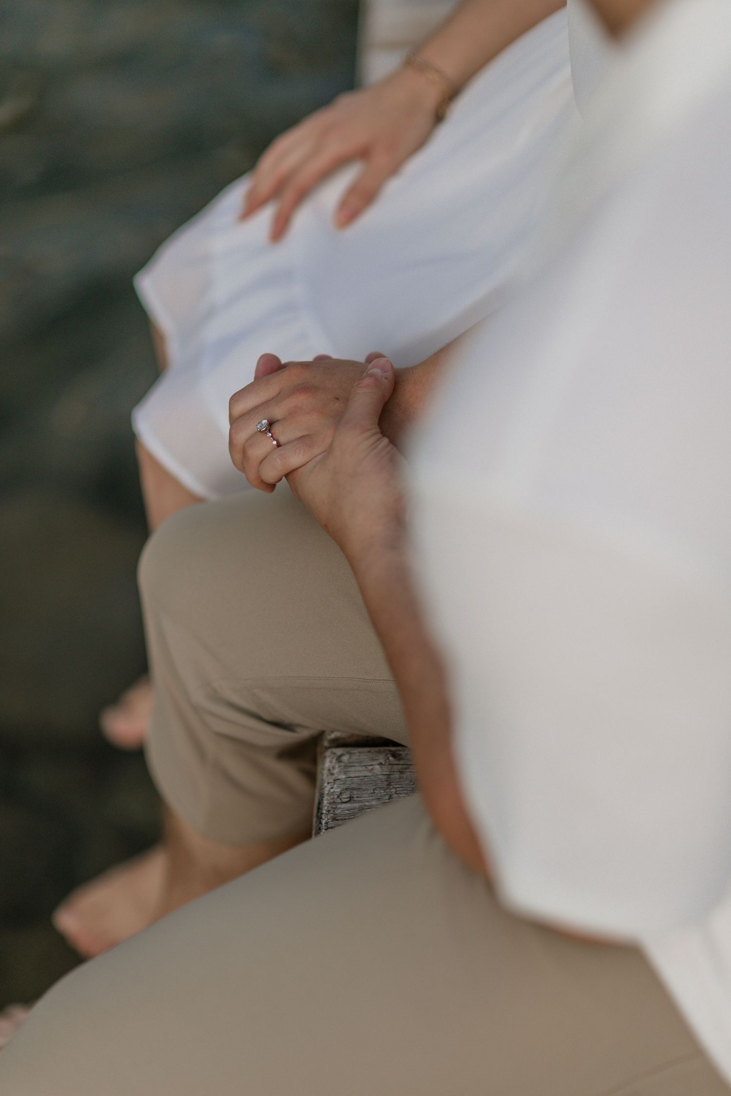 Close-up detail of clasped hands with an engagement ring visible.