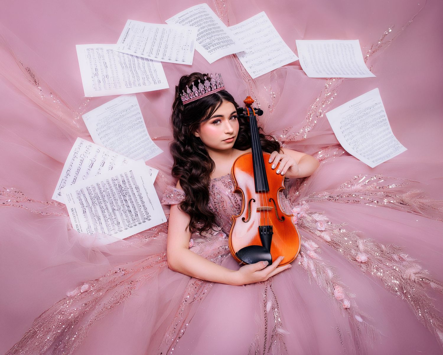 Young girl in pink gown holding violin, wearing tiara, surrounded by floating sheet music in dreamy pink setting.