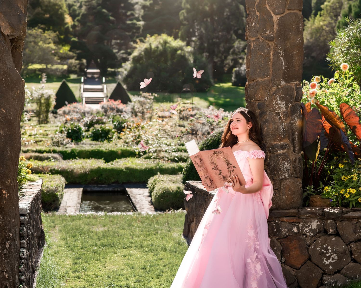 A girl in a pink ball gown reads a book in a sunlit garden with butterflies and lush greenery.