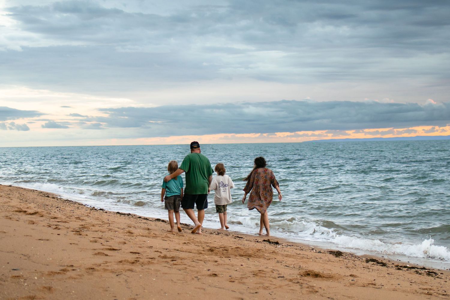 family walking along the beach at sunrise