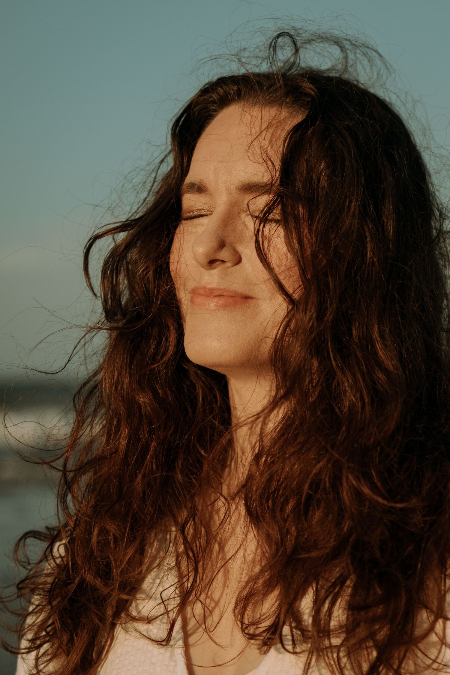 woman looking up into the sun at the beach