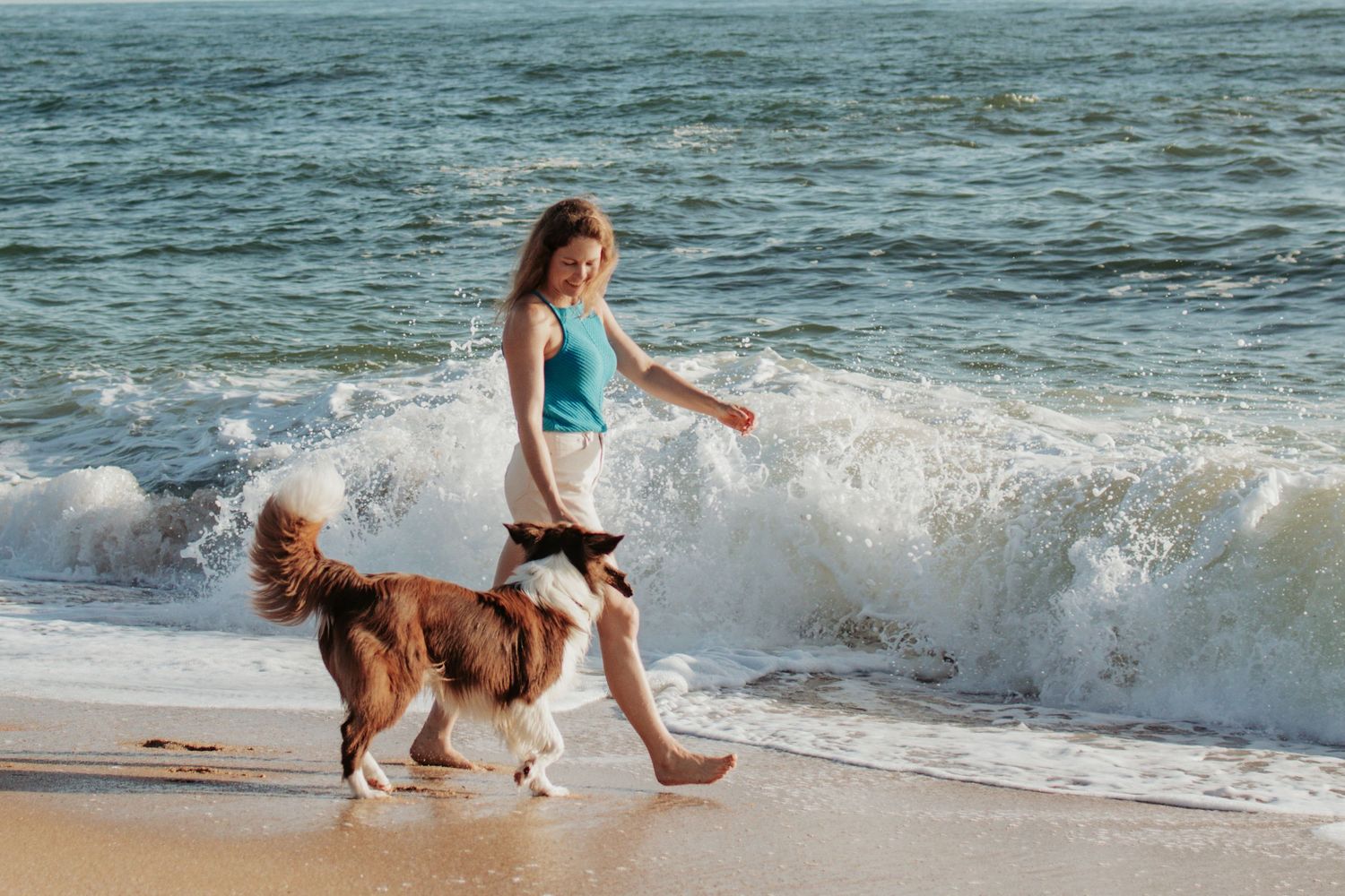 woman and her dog walking along the beach