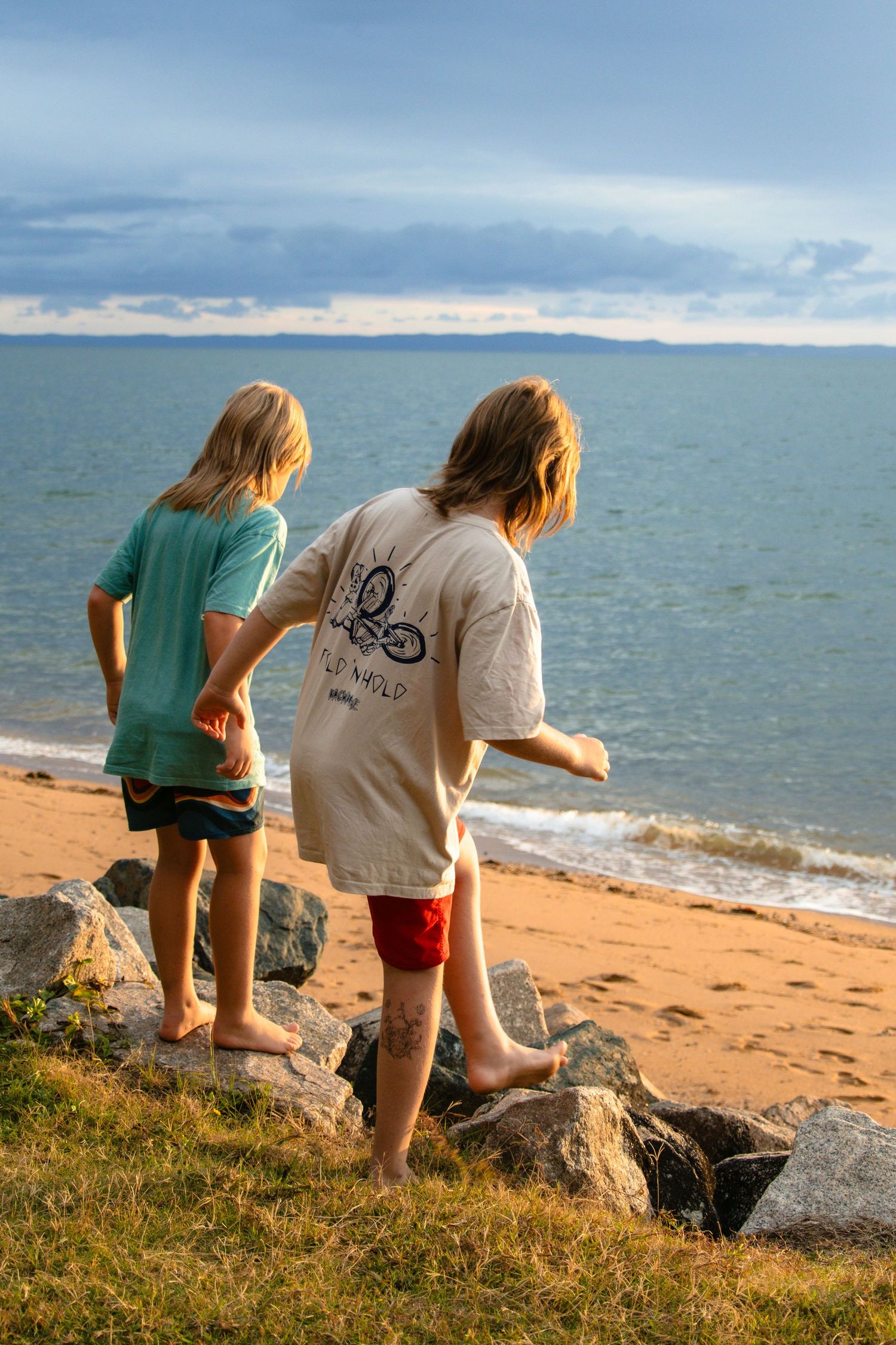 children at sunrise walking down rocks at the beach