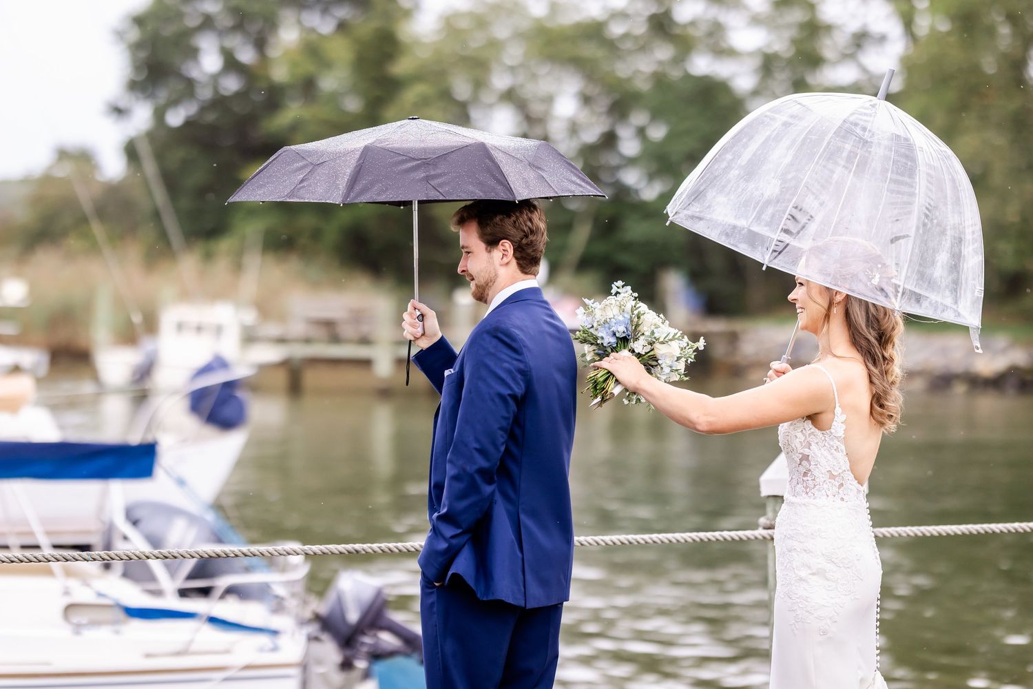Wedding couple sharing a romantic moment under a white umbrella by the waterfront.