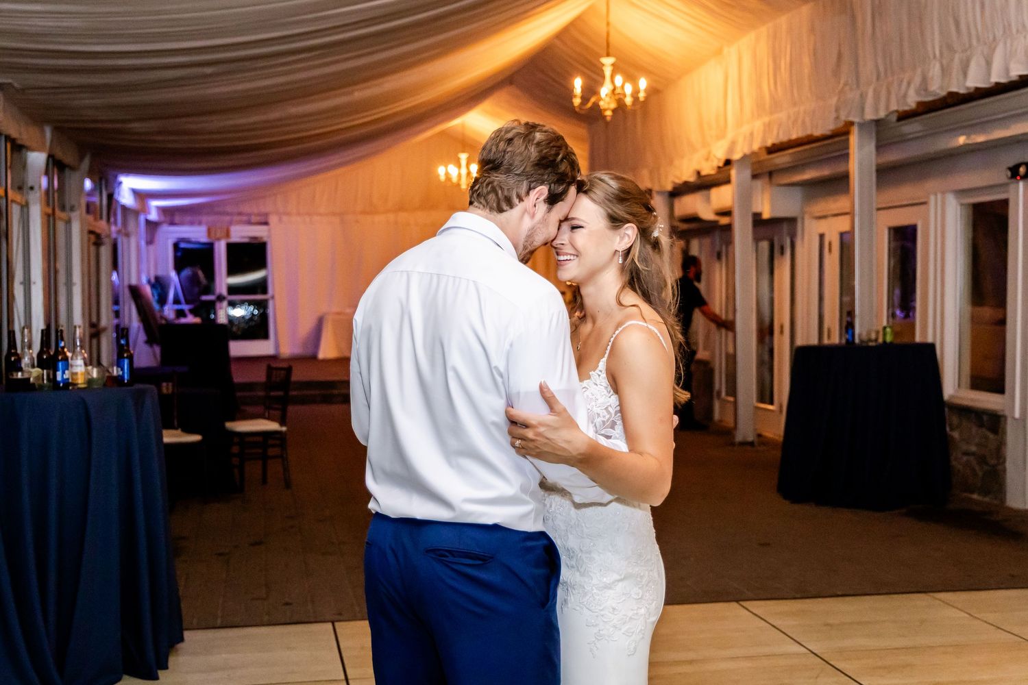Couples dancing together during an evening wedding reception in a beautifully lit white tent venue.