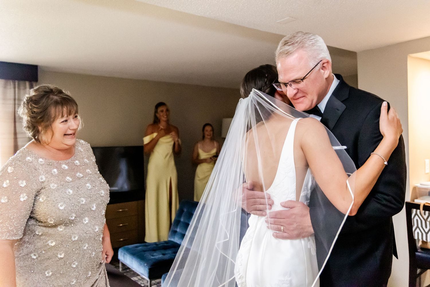 Wedding party members share emotional embraces and moments during preparation in an indoor venue.
