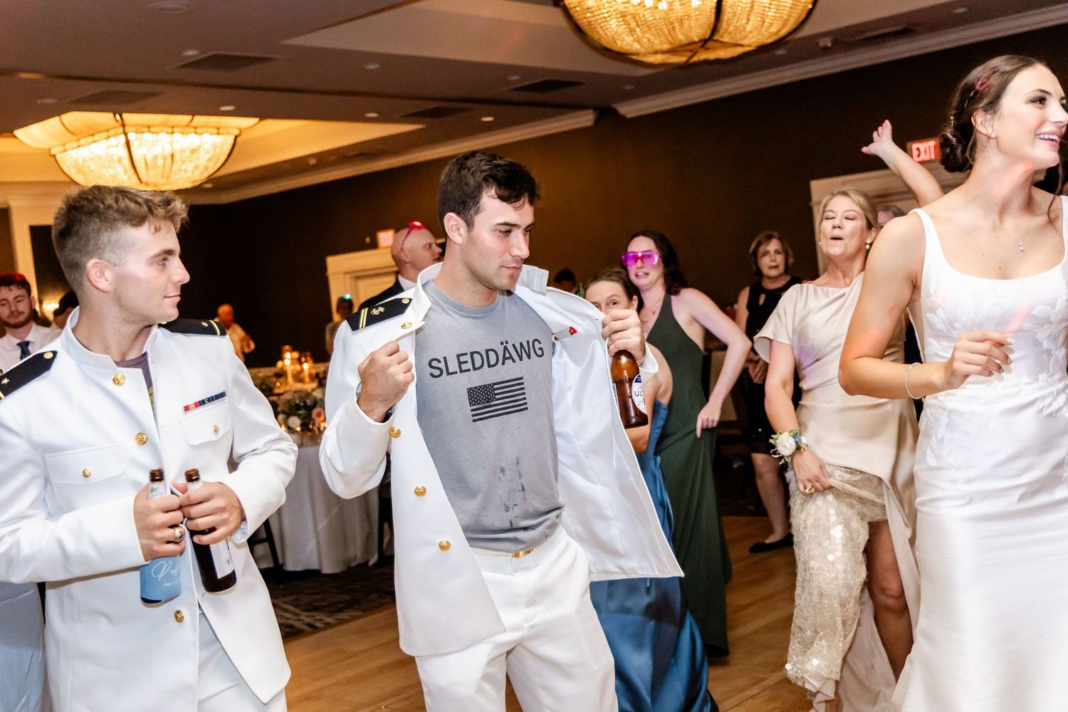 Lively dance floor filled with wedding guests celebrating and moving to the music at an indoor reception.