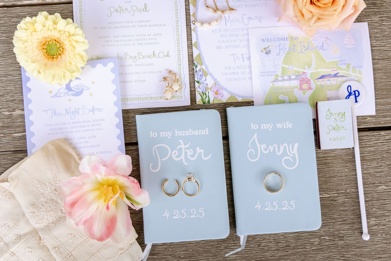 Wedding details including rings, vow books, and peach and yellow flowers arranged on wooden surface.