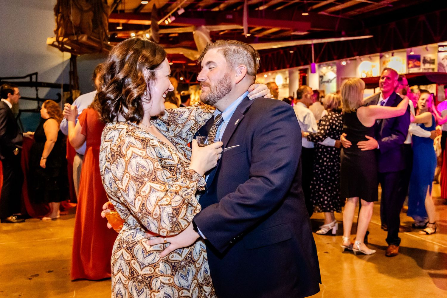 Wedding reception dance floor with warm lighting and exposed wooden beams overhead.