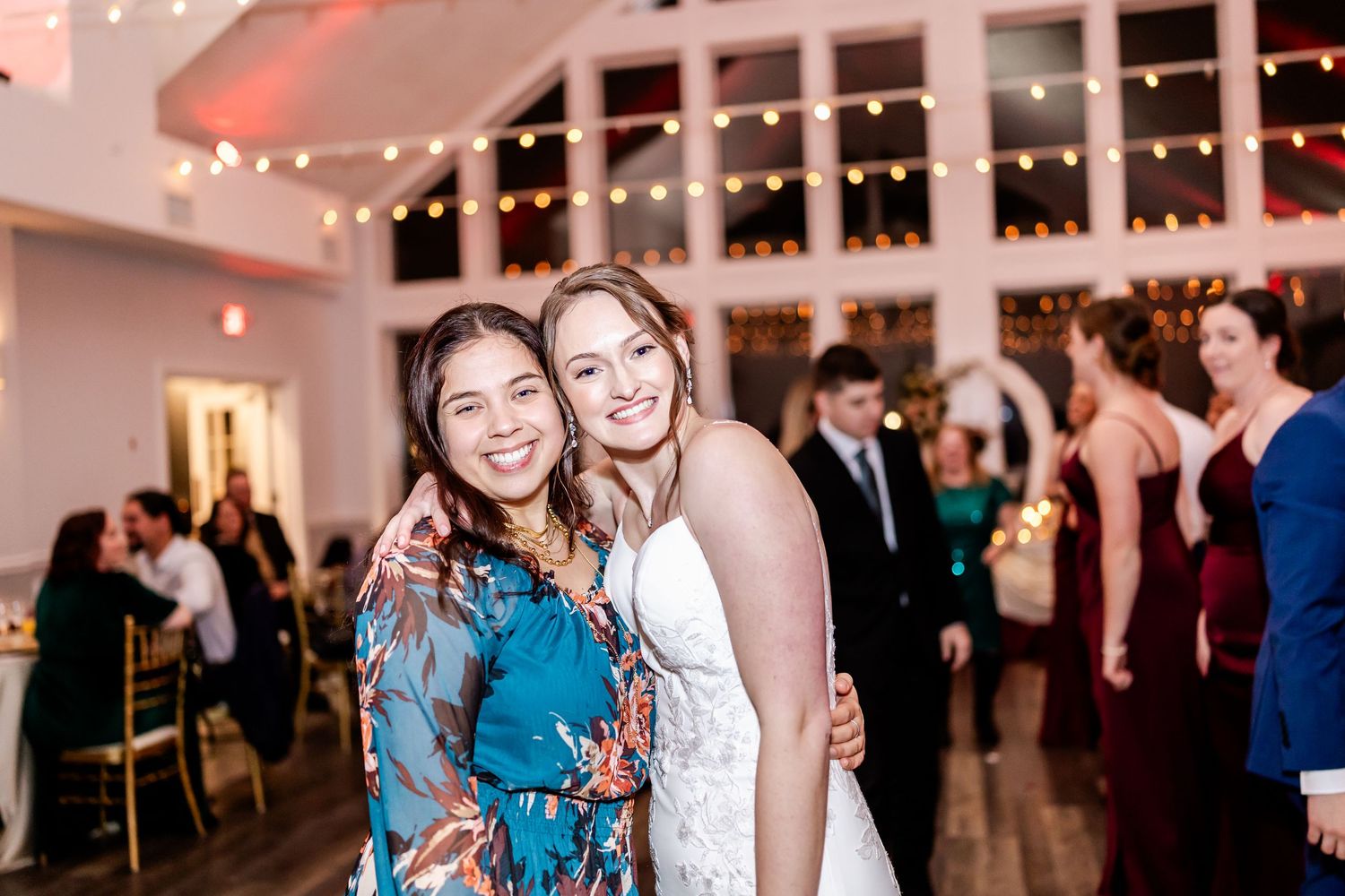 Wedding reception venue decorated with string lights and guests mingling in an elegant ballroom.