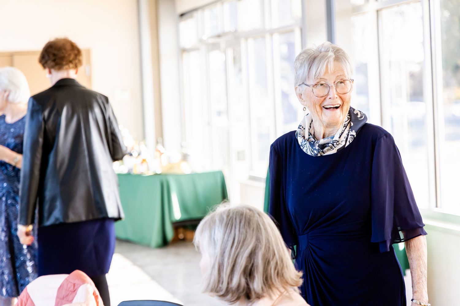 Senior guest in navy blue enjoying conversation at a wedding reception.