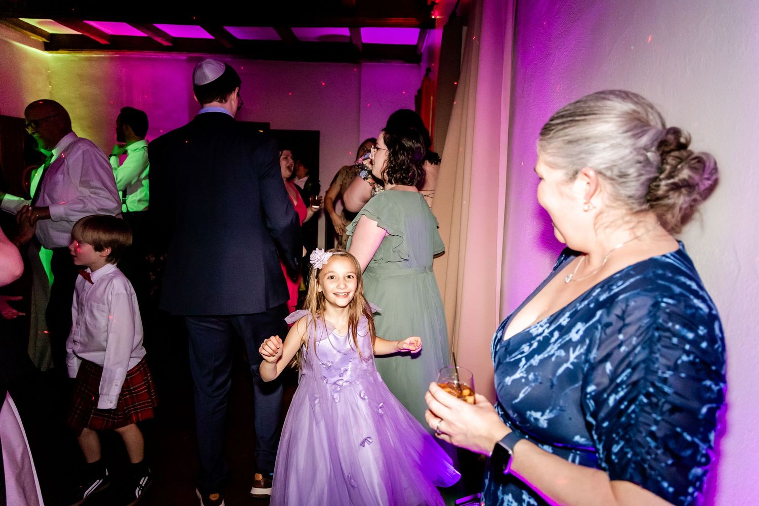 People enjoying a celebration in a room with purple lighting and festive atmosphere.