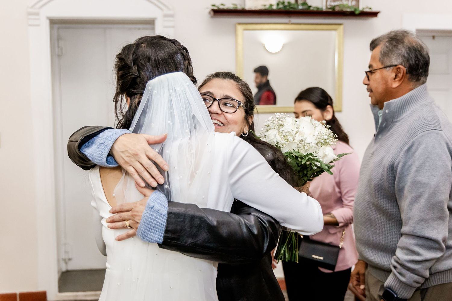 A warm embrace shared between guests during a joyful indoor celebration.