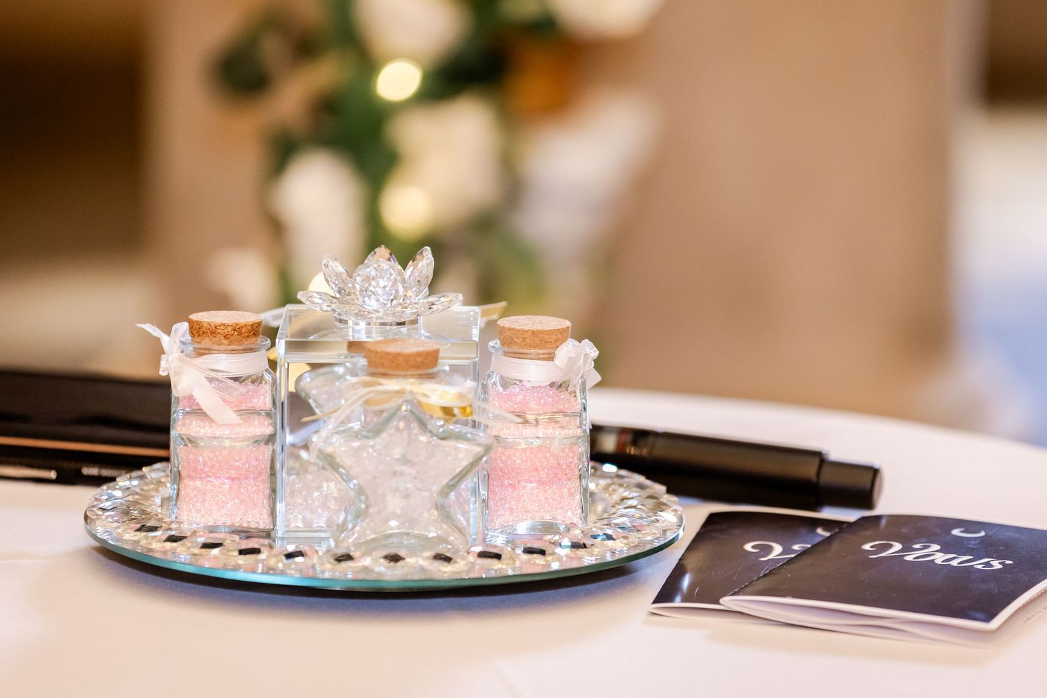Ornate shot glasses with pink accents displayed on a silver tray at an elegant wedding reception.