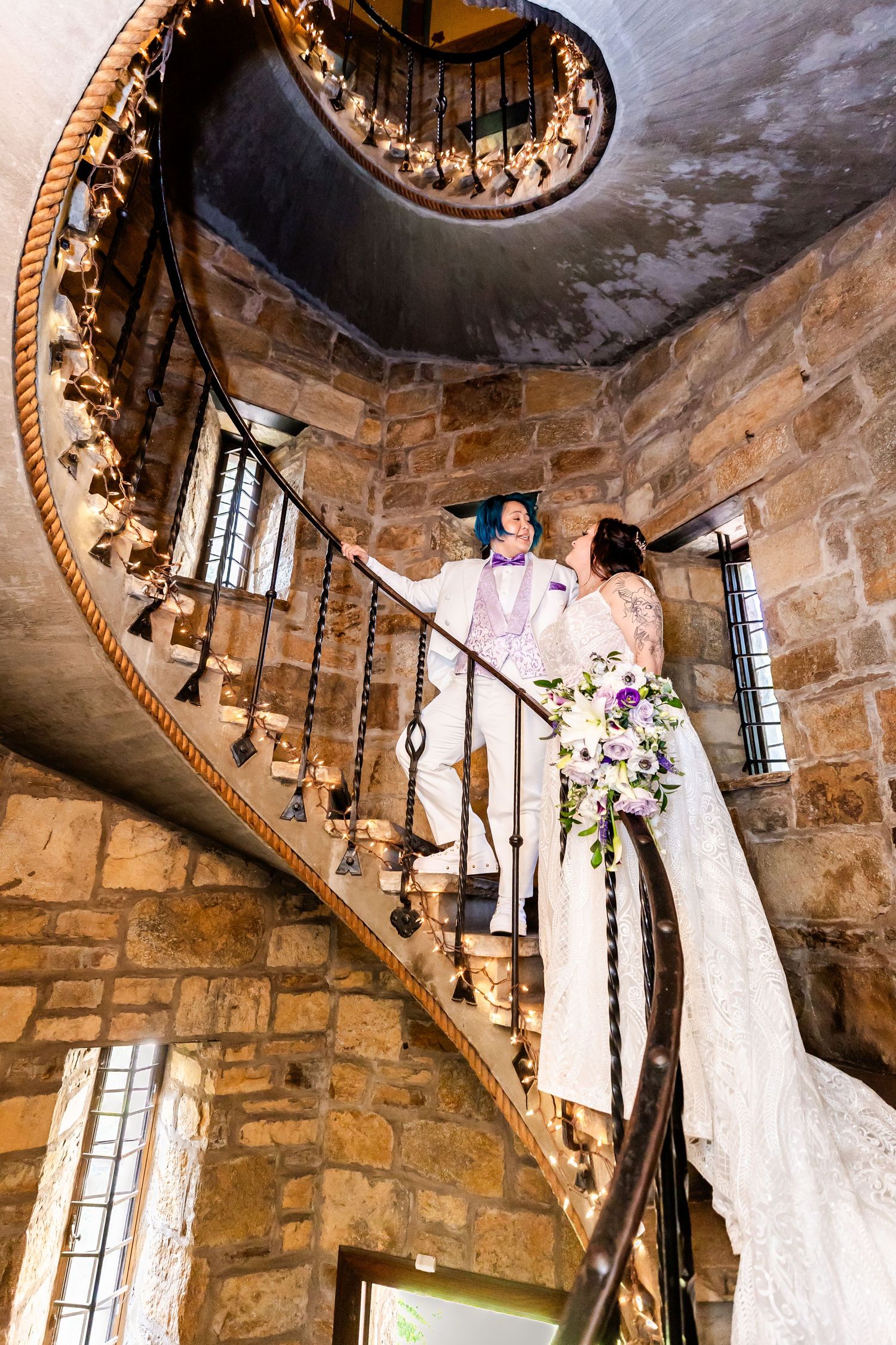 Elegant spiral staircase in stone castle tower with ornate railing and natural lighting through windows.
