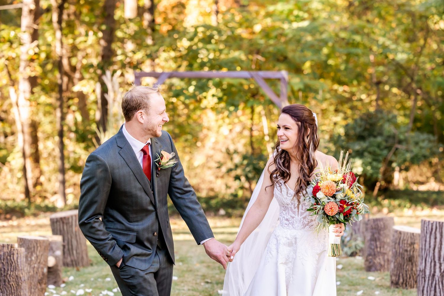 A couple poses for romantic wedding photos in a sunlit autumn forest setting.