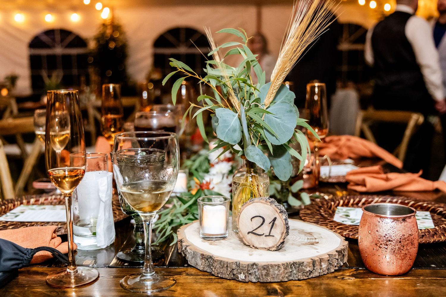 Rustic wedding table decor with candles, greenery, and vintage table numbers on wooden surface.