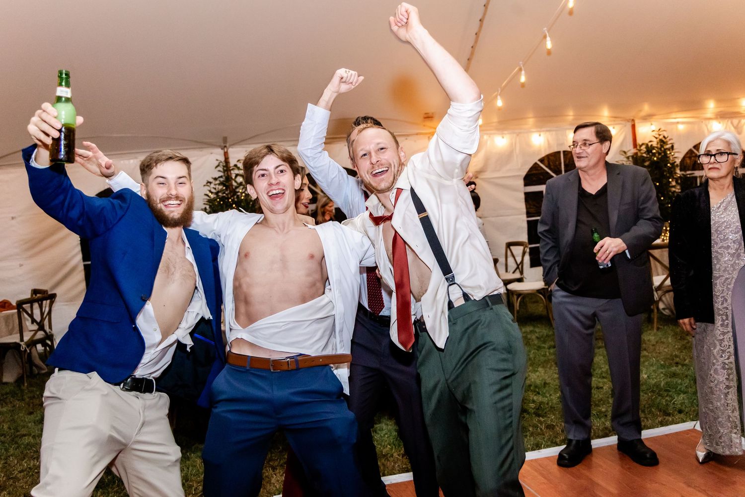 Energetic wedding guests dancing and jumping during reception party celebrations.