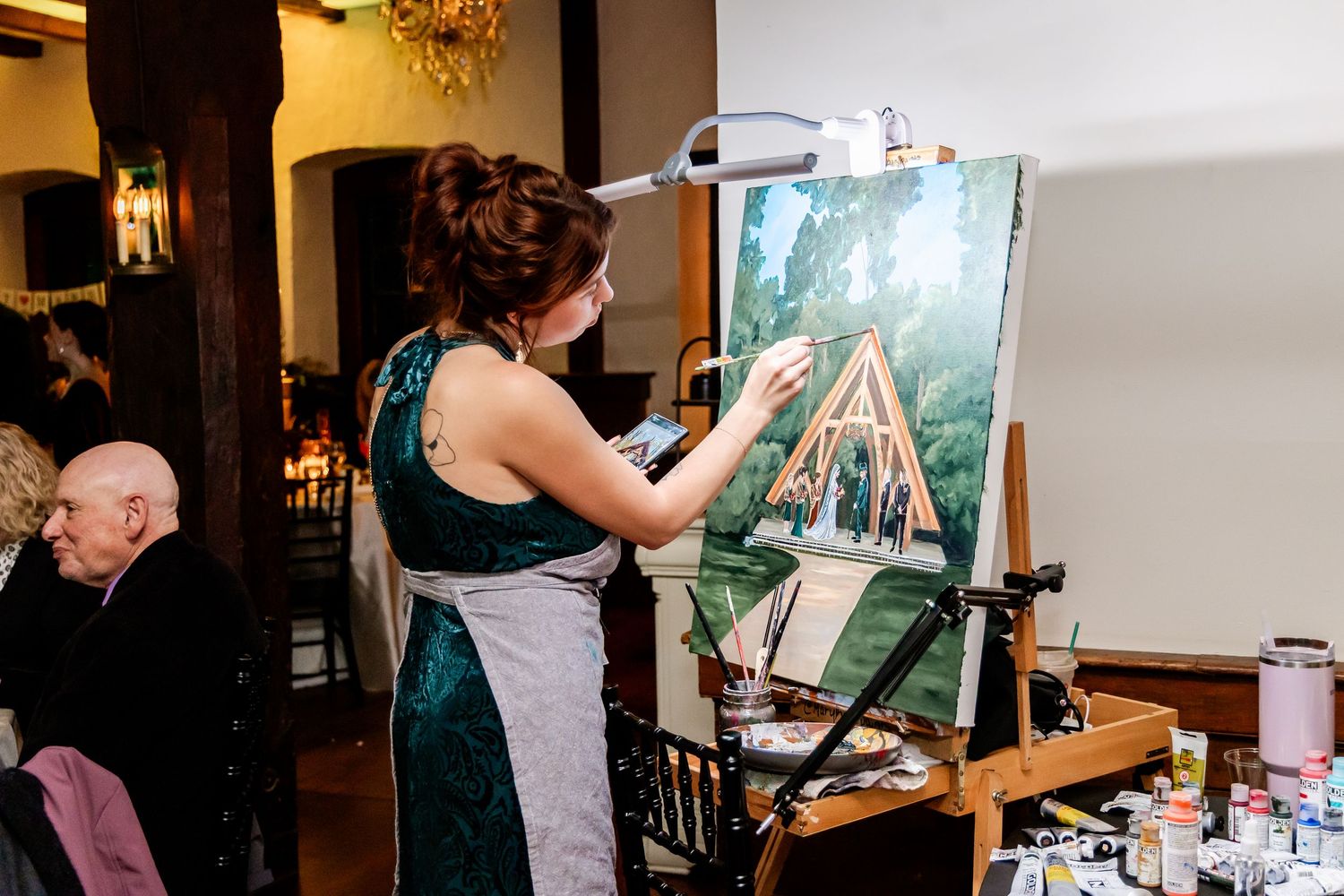 Wedding guests painting at easels during a creative reception activity.