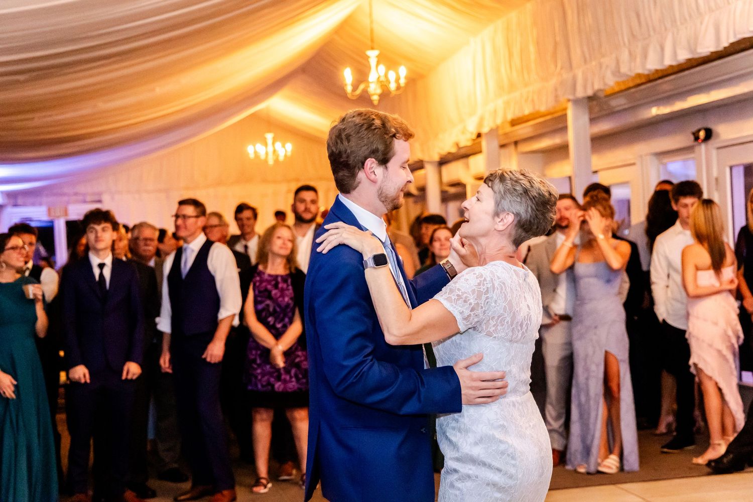 Guests enjoy dancing and mingling at an elegant wedding reception in a warmly lit ballroom.