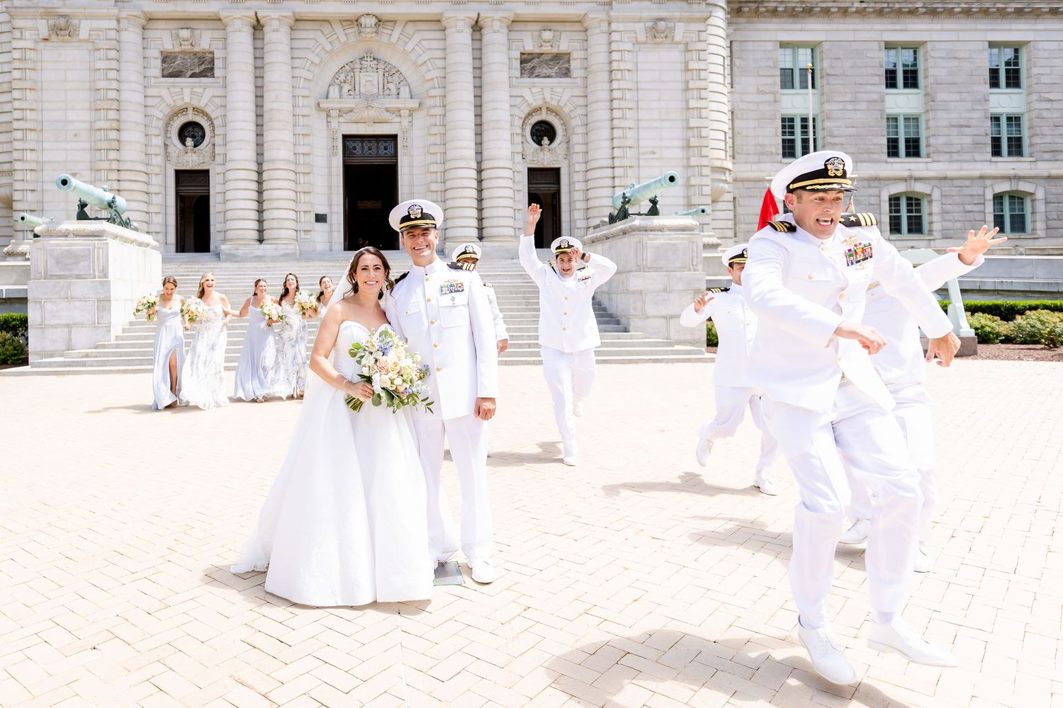 People dressed in all white gather for a dance performance in front of an ornate classical building.