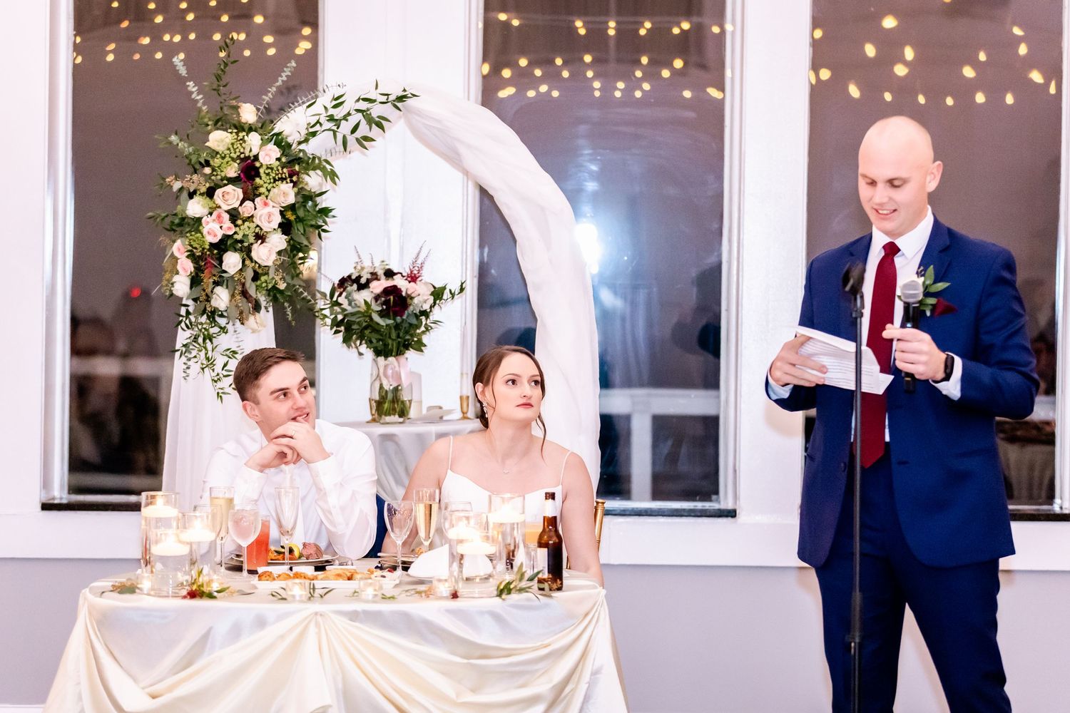 Wedding reception venue decorated with twinkling lights and floral arrangements.